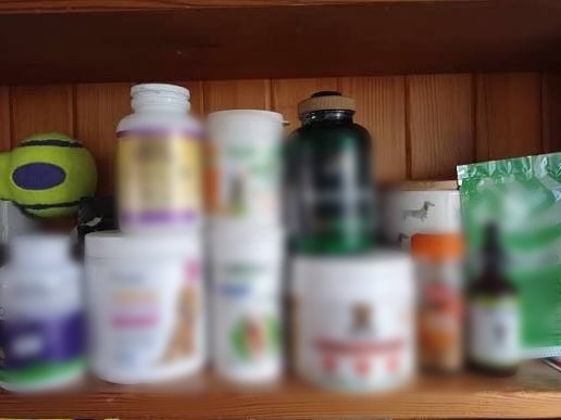 A blurred shelf of various dog supplement bottles